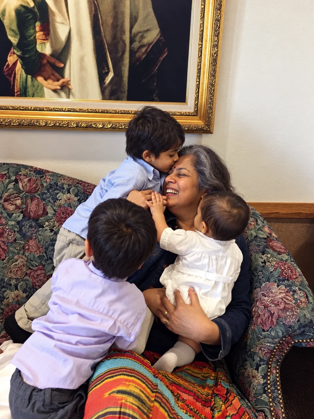 A grandmother laughing as she hugs her three grandchildren